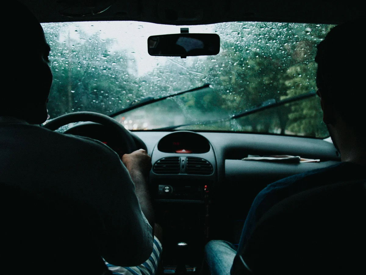 Rain on the windshield, seen from inside a car on a green road