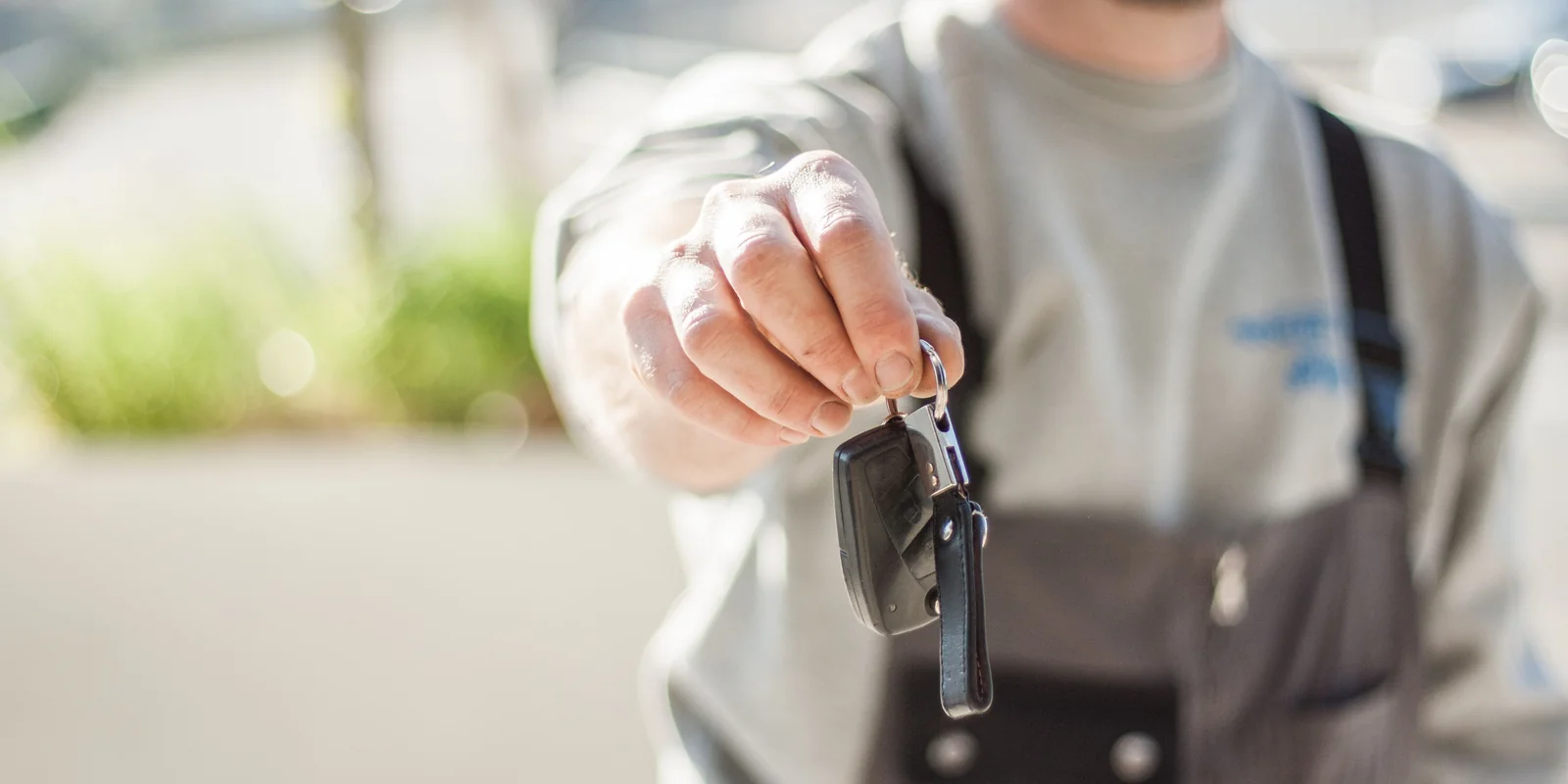 A hand holding out a set of car keys