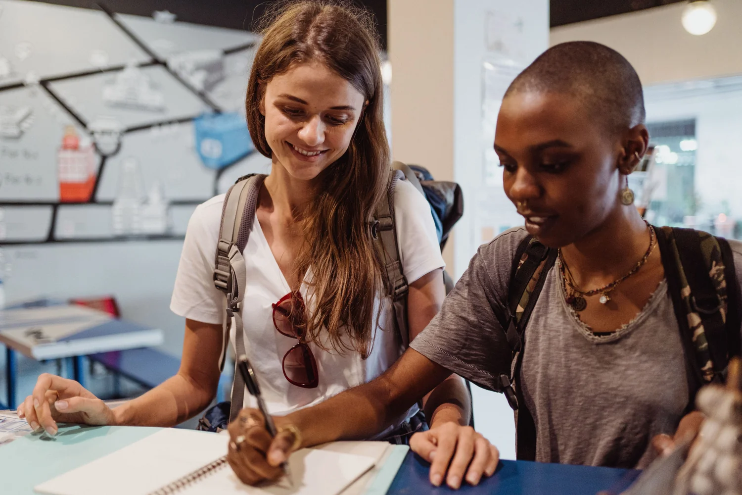 Two travelers filling in paperwork at a counter